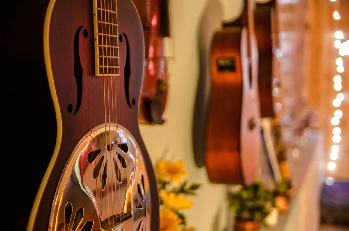 Resonator and acoustic guitars on a warmly lit studio wall
